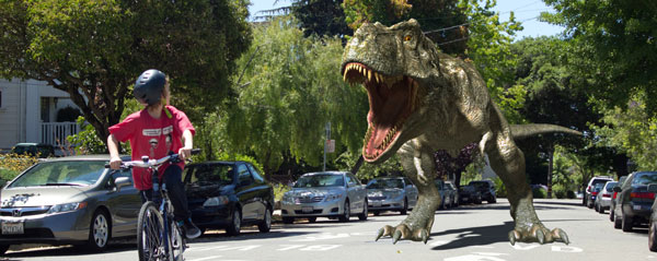 Kid riding bike away from T-Rex